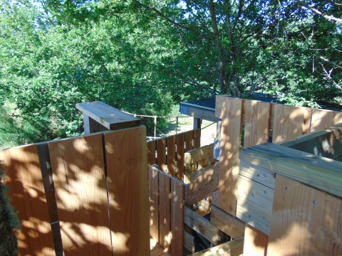 Houten boomhutconstructie omringd door groen bij 'Eco-Chalet EXTRA' op Camping Junora, Frankrijk.