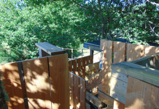 Houten boomhutconstructie omringd door groen bij 'Eco-Chalet EXTRA' op Camping Junora, Frankrijk.