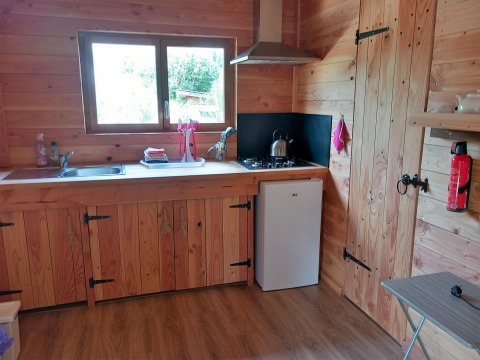 Cucina in legno di uno chalet eco-lusso autosufficiente al Campeggio Junora in Francia, con mini frigo.