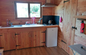 Trækøkken i et selvforsynende luksus-eco-chalet på Camping Junora i Frankrig med gaskomfur og mini-køleskab.