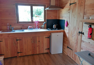 Wooden kitchen in a self-sufficient luxury eco-chalet at Campsite Junora, France, featuring a mini fridge.