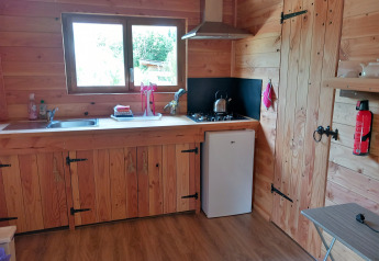 Cocina de madera en un eco-chalet autosuficiente y lujoso en el Camping Junora, Francia, con frigorífico pequeño.