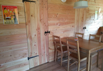 Træbeklædt spisestue med fire stole, et bord, en plakat og moderne belysning i et luksuriøst øko-chalet.