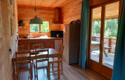 Interior of a self-sufficient luxury eco-chalet at Campsite Junora, featuring dining area, kitchen and terrace.