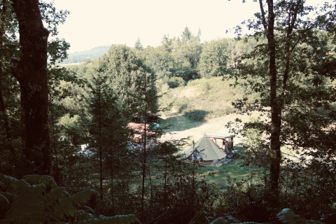 Blick auf ein Zeltlager im Grünen bei Bell tent «6M» am Campsite Junora, umgeben von Wäldern in Frankreich.