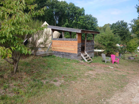 Wooden lodge and canvas bell tent at Bell tent «6M» at Campsite Junora, France, surrounded by green trees.