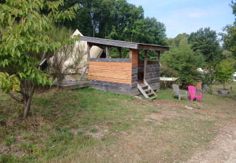 Holzhütte mit Zelt im Hintergrund bei Bell tent «6M» auf dem Campsite Junora in Frankreich, Natur ringsum.