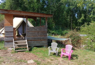 Outdoor view at Bell tent «6M» at Campsite Junora in France, showing tent, shelter, lawn chairs and hammock.