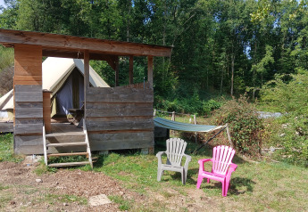 Scène extérieure à la tente Bell «6M» au camping Junora en France avec tente, abri, chaises et hamac.