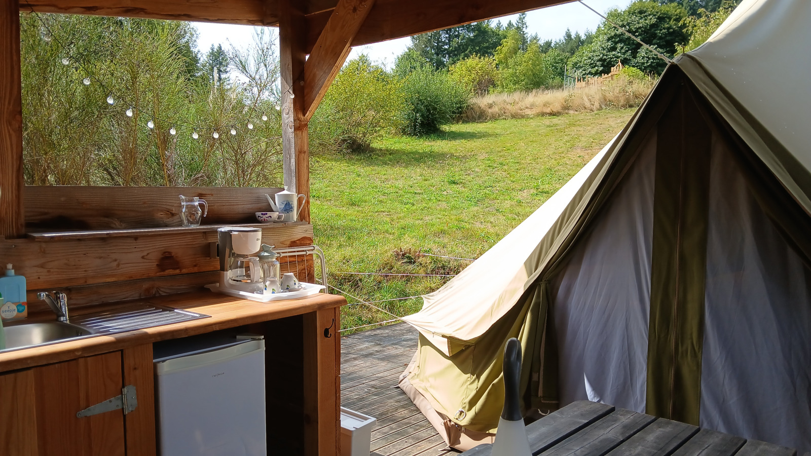 Buitenkeuken en tent bij Bell tent '6M' op Camping Junora, Frankrijk, met uitzicht op groen landschap.