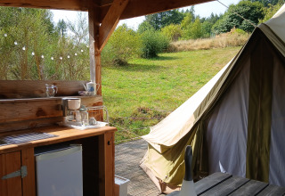 Outdoor kitchen and tent at Bell tent ‘6M’ at Campsite Junora, France, in a scenic green natural setting.