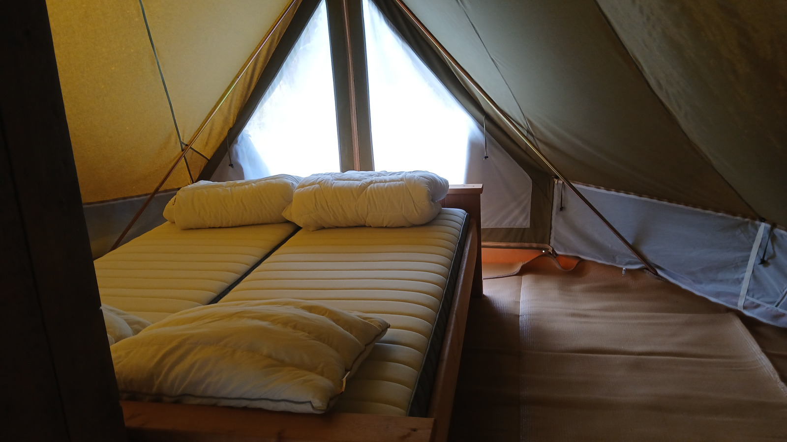 Interieur van Bell tent «6M» op Camping Junora in Frankrijk, met comfortabel tweepersoonsbed in beeld.