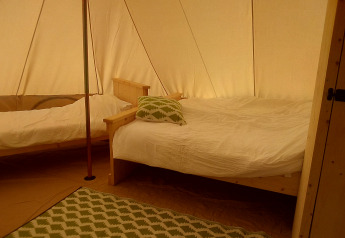Innenansicht eines Bell Zelts auf dem Campingplatz Junora in Frankreich mit zwei Holzbettgestellen und grünem Teppich.