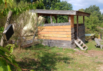 Abri en bois et chaises près de la tente Bell 6M au camping Junora, France, par une journée ensoleillée.