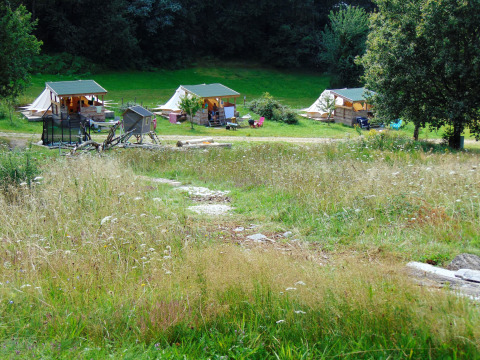 View of Bell tent “6M” at Campsite Junora in France, showing tents and lush green surroundings.