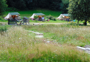 Blick auf Bell tent «6M» beim Campingplatz Junora in Frankreich mit grüner Wiese und Zelten.
