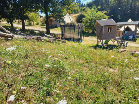 View of Bell tent ‘6M’ at Campsite Junora, France featuring tents, a trampoline, and a playground hut.