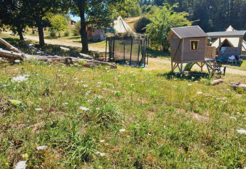 Blick auf das Bell-Zelt «6M» am Campingplatz Junora in Frankreich mit Zelten, Trampolin und Spielhaus.