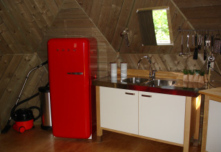 Petite cuisine d’igloo en bois avec réfrigérateur rouge rétro et évier au Holiday Park Delftse Hout.