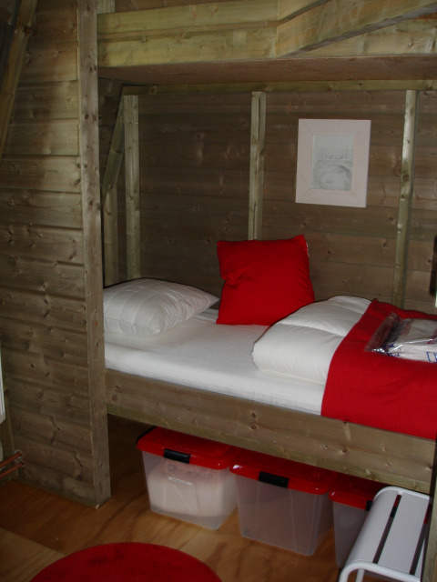 Coin nuit chaleureux dans une tiny house Wooden Igloo avec des touches rouges au Holiday Park Delftse Hout.