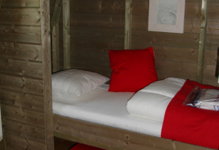 Gemütlicher Schlafbereich in einem Wooden Igloo Tiny House mit roten Akzenten im Ferienpark Delftse Hout.