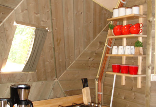 Pequeña cocina en el Wooden Igloo de Holiday Park Delftse Hout, Países Bajos, con estantería y tazas.