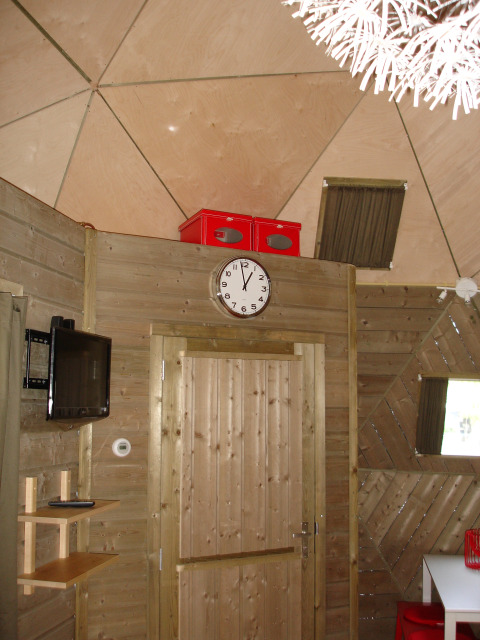 Innenaufnahme des kleinen Holzhauses Wooden Igloo im Holiday Park Delftse Hout, Niederlande, mit Uhr.
