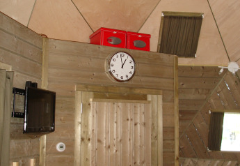 Vista interna della tiny house Wooden Igloo all'Holiday Park Delftse Hout, Olanda, con orologio e TV.
