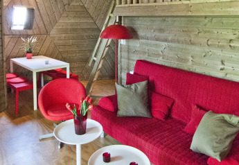 Stue i tiny house Wooden Igloo, Holiday Park Delftse Hout, med rød sofa, spisebord og unik lampe.