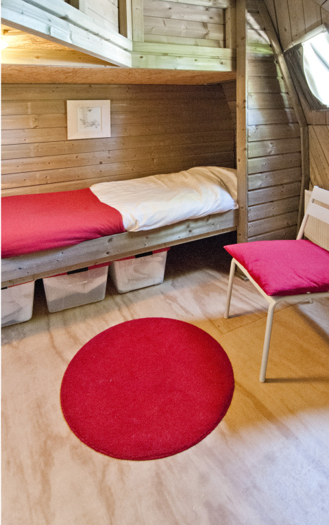 Cozy sleeping area in the Wooden Igloo at Holiday Park Delftse Hout, with wood paneling and red accents.