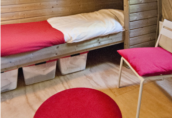Knusse slaapruimte in de Wooden Igloo bij Holiday Park Delftse Hout, met houten wanden en rode accenten.