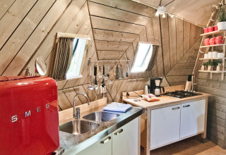 Modernes Küchenbereich im Tiny House Wooden Igloo im Holiday Park Delftse Hout, Niederlande, mit rotem SMEG-Kühlschrank.