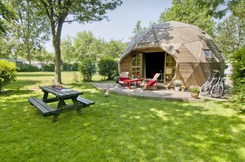 Tiny house Wooden Igloo au Holiday Park Delftse Hout, Pays-Bas, avec vélos, banc et pelouse verte.