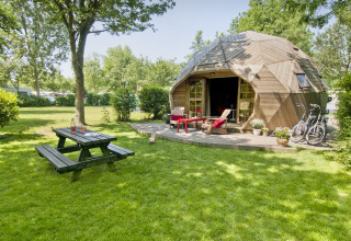 Tiny house Wooden Igloo presso Holiday Park Delftse Hout, Paesi Bassi, con bici, panca e prato verde.