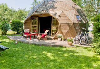 Træiglo-tiny house med terrasse og cykler i grøn have ved Holiday Park Delftse Hout, Holland.