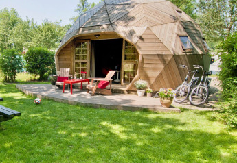 Tiny house igloo en bois avec terrasse, chaises et vélos dans un jardin à Delftse Hout, Pays-Bas.