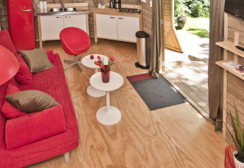 Innenraum des Tiny House Wooden Igloo im Holiday Park Delftse Hout, Niederlande, mit roter Einrichtung.