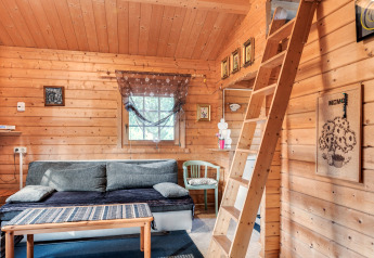 Lyst trækabineinteriør i Niederaula, Tyskland, med sofa, trappe til hems og dekorative billeder.