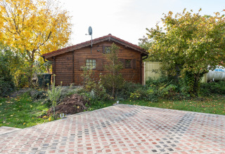 Træhytte kaldet 'Niederaula' i Tyskland med brostensbelagt gårdsplads og omgivet af grønne træer.
