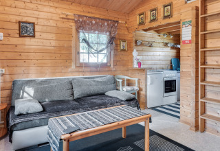 Hyggelig stue i træhytte 'Niederaula' i Tyskland med sofa, køkken og dekorerede vægge.
