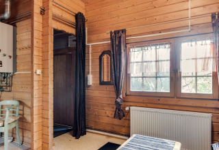 Interior of a wooden cabin with large windows, curtains, and radiator heater at Niederaula in Germany.