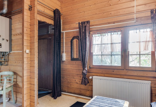 Indretning af en træhytte med store vinduer, gardiner, radiator og synlige rør i Niederaula, Tyskland.