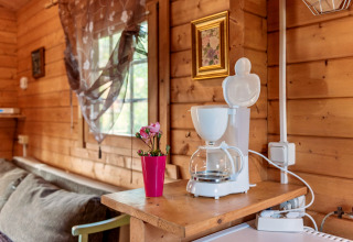 Cozy wooden cabin ‘Niederaula’ in Germany, featuring a coffee maker, flowers, and sunlight through window.