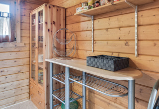 Træbeklædt hjørne i en hytte med opbevaringsreol, glasvitrine og hylder, set i Niederaula, Tyskland.