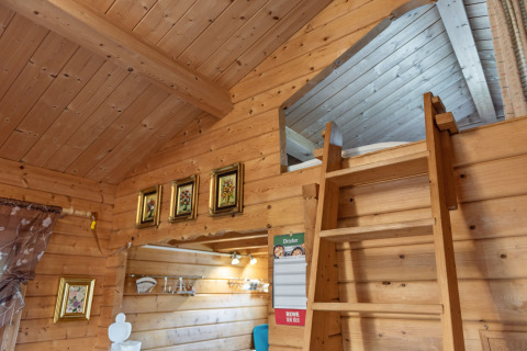 Træinteriør af en hyggelig bjælkehytte i Niederaula, Tyskland, med stige til hems og dekorationer.