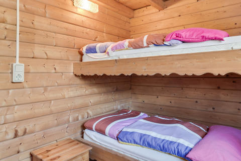 Træbeklædt værelse med køjesenge og farverige dyner i en hyggelig hytte i Niederaula, Tyskland.