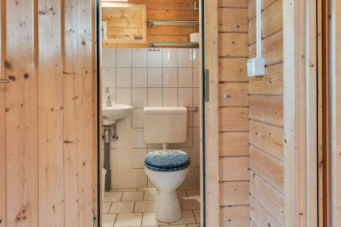 Et lille badeværelse i en træhytte ved Niederaula i Tyskland med toilet, håndvask og flisevægge.