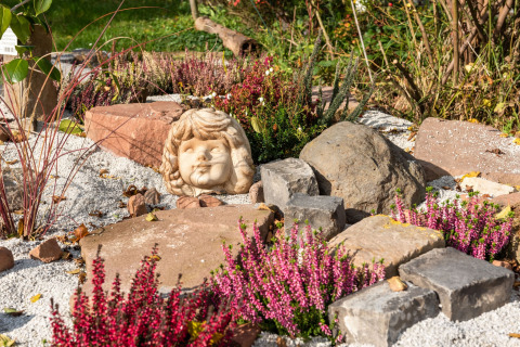 Stenhavedekoreret have med lilla lyng og en skulptur af et barnehoved ved hytten Niederaula, Tyskland.