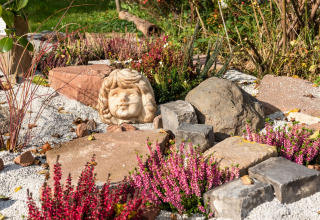 Stenhavedekoreret have med lilla lyng og en skulptur af et barnehoved ved hytten Niederaula, Tyskland.