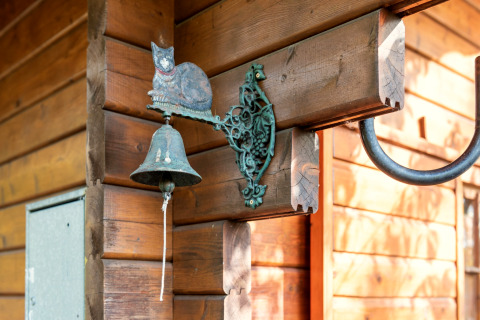 Decorative cat-themed door bell mounted on wooden wall at Niederaula cabin in Germany.